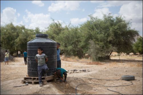 Palestinian children from the West Bank village of Fasayel, Jordan valley, play by a water tank in the village. May 14, 2015. Photo by Miriam Alster/FLASH90